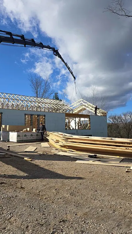 Crane lifting roof trusses new home framing