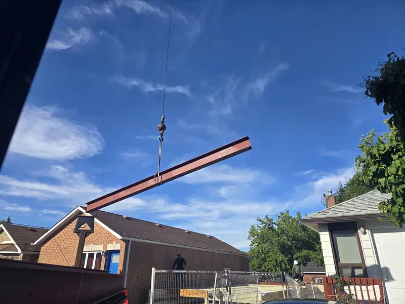 Crane lifting steel beam home renovation