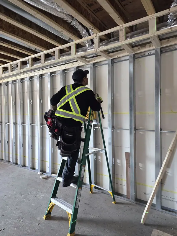 Worker installing interior steel stud walls